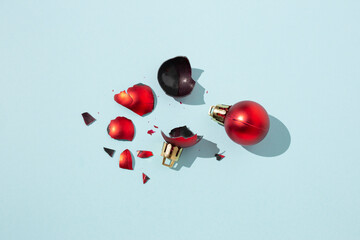 Whole and broken red Christmas balls arranged on blue background in bright studio