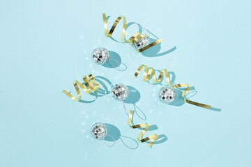 Shiny Christmas baubles in shape of disco balls placed on blue background in studio