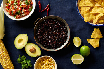 Ingredients for cooking chilaquiles - black beans, tortilla chips, corn and salsa