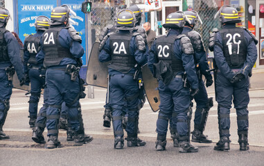 policiers anti émeute en tenue de protection face à des manifestants en attente d'intervention