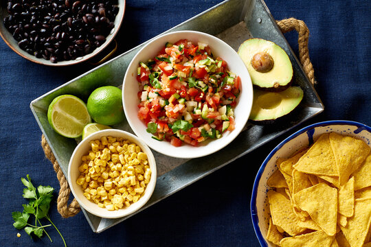 Ingredients for cooking chilaquiles - black beans, tortilla chips, corn and salsa