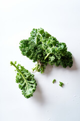 Green curvy kale leaves tied with twine on white background