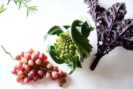 Flatlay with purple kale, pink grapes and romanesco cabbage