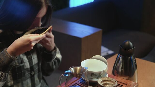 Young woman snuffs chinese tea leaves in plate. Traditional eastern chinese tea ceremony.