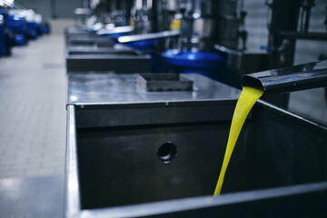 Closeup of yellow chemical liquid flowing from metal tap in industrial area of modern plant