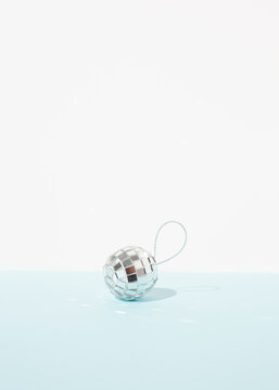 Miniature glowing disco ball placed on table as Christmas decoration on blue background
