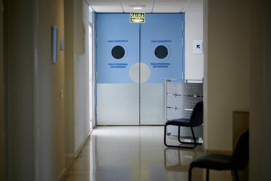 Doors in empty passage with glowing tiled floor illuminated by lamps in modern clinic