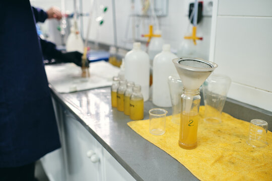 Funnel in glass vial with yellow chemical liquid placed on table in modern laboratory