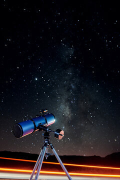 Modern optical telescope against cloudless dark sky with glowing stars at night time