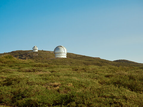 Largest optical reflecting telescope Gran Telescopio Canarias located on grassy hilltop against clear blue sky at astronomical observatory on island of La Palma in Spain
