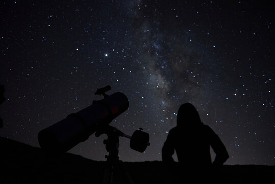 Silhouettes of anonymous scientist using telescopes while exploring night starry sky with milky way in darkness