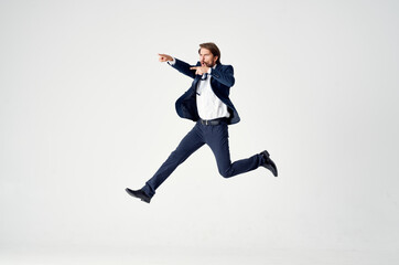 Fototapeta na wymiar Energetic business man in a blue suit jumps up on a light background success joy emotions