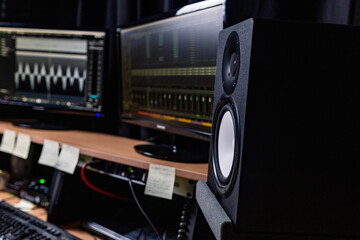 Contemporary stereo speaker placed on table with monitors in dark music recording studio