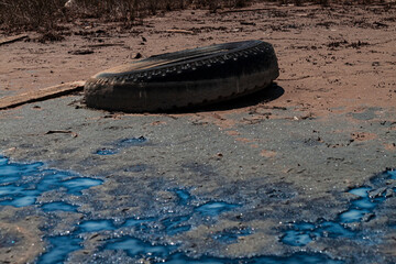 Waste by the ocean. Decaying discarded truck tire. A river of toxic chemical waste