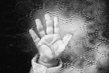 A print of the child's hand on the corrugated glass. Soft focus. Black and white image.