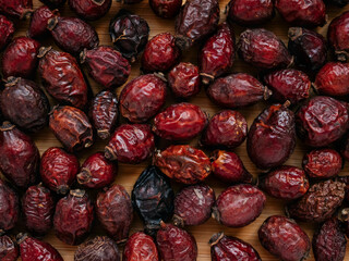 Dried berries of Dog Rose or Rosa canina. Dry fruits of sweet-brier or rose hips on wooden background. Healthy and herbal concept. Selective focus. Natural vitamin, nutritional supplement for health