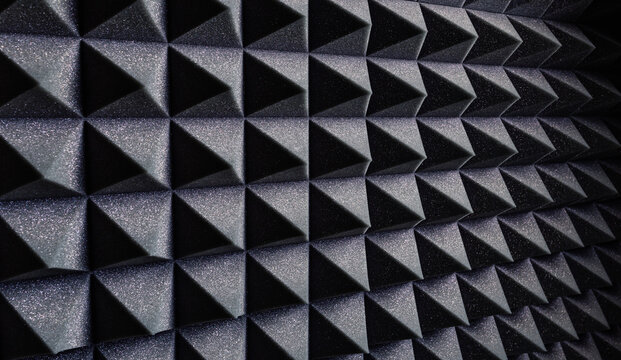 Textured background of wall with black geometric soundproof foam with pyramid shaped pattern in recording studio
