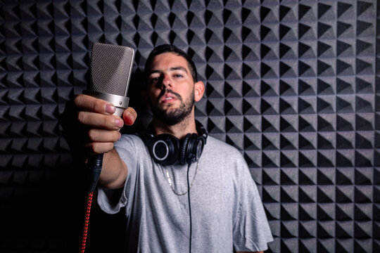 Talented male singer with modern microphone standing in acoustic soundproof room in music recording studio and looking at camera