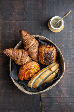 Top view of basket full of delicious homemade croissants and buns on wooden table at home