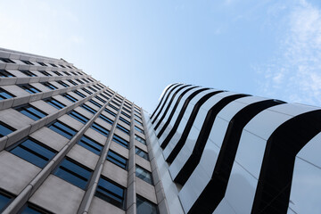 Low angle of tall contemporary multi storey construction under light blue sky in sunlight in daytime