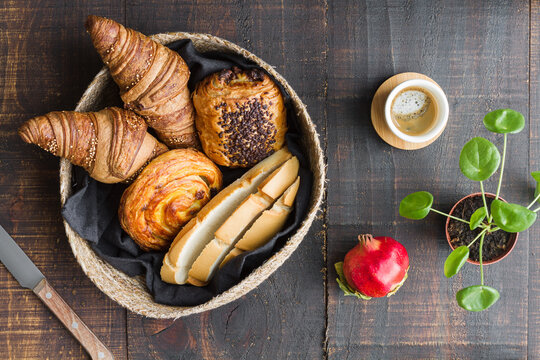 Top view of arrangement of buns and cups of coffee on wooden table for delicious breakfast at home