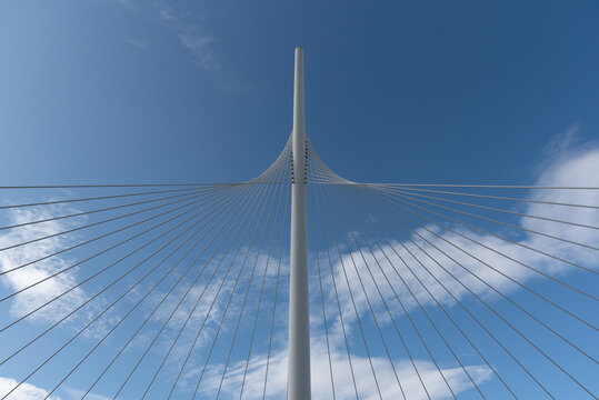 Fototapeta From below of white contemporary suspension bridge with high column connecting many cables together against blue sky