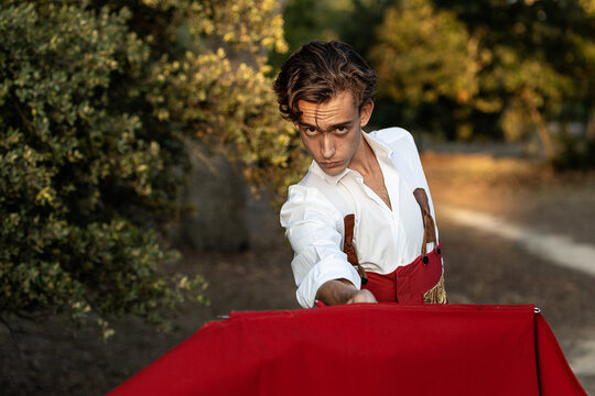 Determined young male toreador in red traditional costume performing in nature before corrida and looking at camera