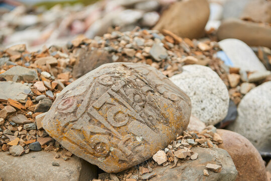 From above of big rock for praying with mantra om mani padme hum in Sanskrit placed in pile