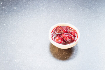 Red fruits jam with berries on a dark kitchen top
