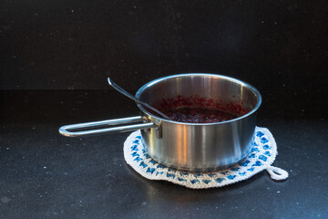 Preparing Cranberry sauce in a metal pan on a dark background