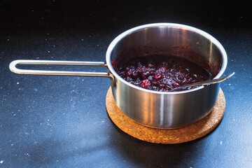 Making jam of red berries on a metal cooking pot