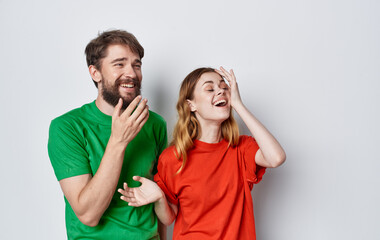 young cheerful couple emotions multicolored t-shirts studio isolated background