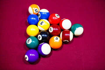 Group of snooker multicolored balls lays as pyramid on the table. Closeup view. Billiard red table with cue and balls. Leisure, hobby and entertainment concept