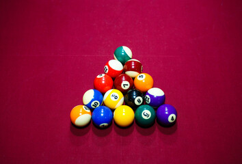 Group of snooker multicolored balls lays as pyramid on the table. Closeup view. Billiard red table with cue and balls. Leisure, hobby and entertainment concept