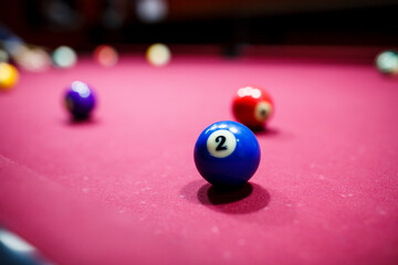 group of snooker multicolored balls lays on the table. Closeup view. Billiard red table with cue and balls. Leisure, hobby and entertainment concept