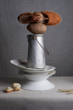 Still life composition of ceramic dishes and iron tin near piece of bread and wheat on table