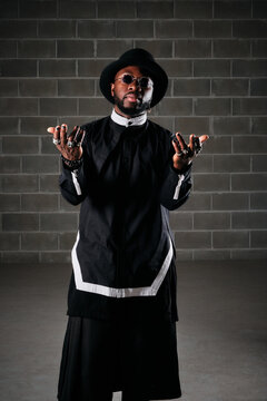 African American male in black clothes and stylish round sunglasses standing in underground garage and looking at camera