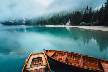 From above wooden boat with paddles floating on turquoise water of calm lake on background of majestic landscape of highlands