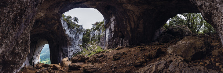 Picturesque view of bristly cave and mounts near growing trees in Basque Country