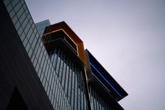 Bottom view of modern building with glass windows, gloomy sky during day