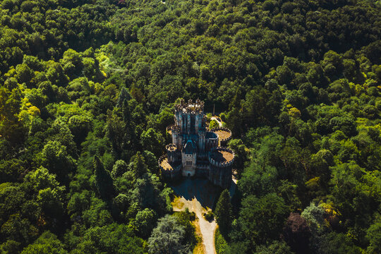 Aerial view of aged stone building surrounded by lush green woods near narrow pathway in Basque Country