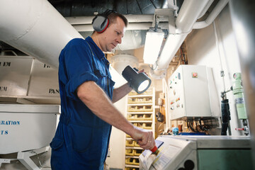 Marine engineer officer controlling vessel enginesand propulsion in engine control room ECR. Ship onboard maintenance