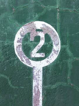 Weathered green wall with peeling paint and number two showing concept of winner