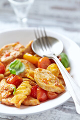 Pasta with chicken breast, cherry tomatoes and fresh basil. Bright wooden background. Close up.	