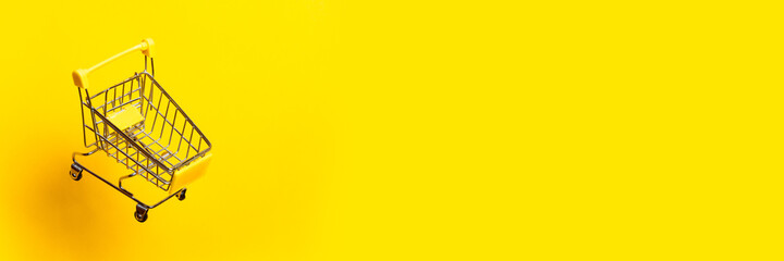 flying empty trolley on a bright yellow background. Close-up. Banner. - obrazy, fototapety, plakaty