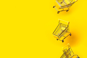 flying in the air three empty trolleys on a bright yellow background. Close-up.