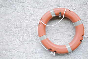 Orange lifebuoy hang on a gray stone wall, symbolic financial rescue package, space for text, no...