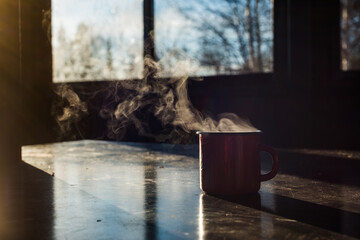 a red coffee mug sits on the table, steaming