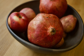 Pomegranate (Punica granatum) fruit in a black  (reduced) pottery bowl.