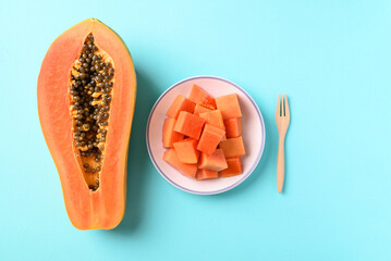 Sliced ripe papaya fruit on plate with fork ready to eating on pastel color background, Tropical fruit, Top view